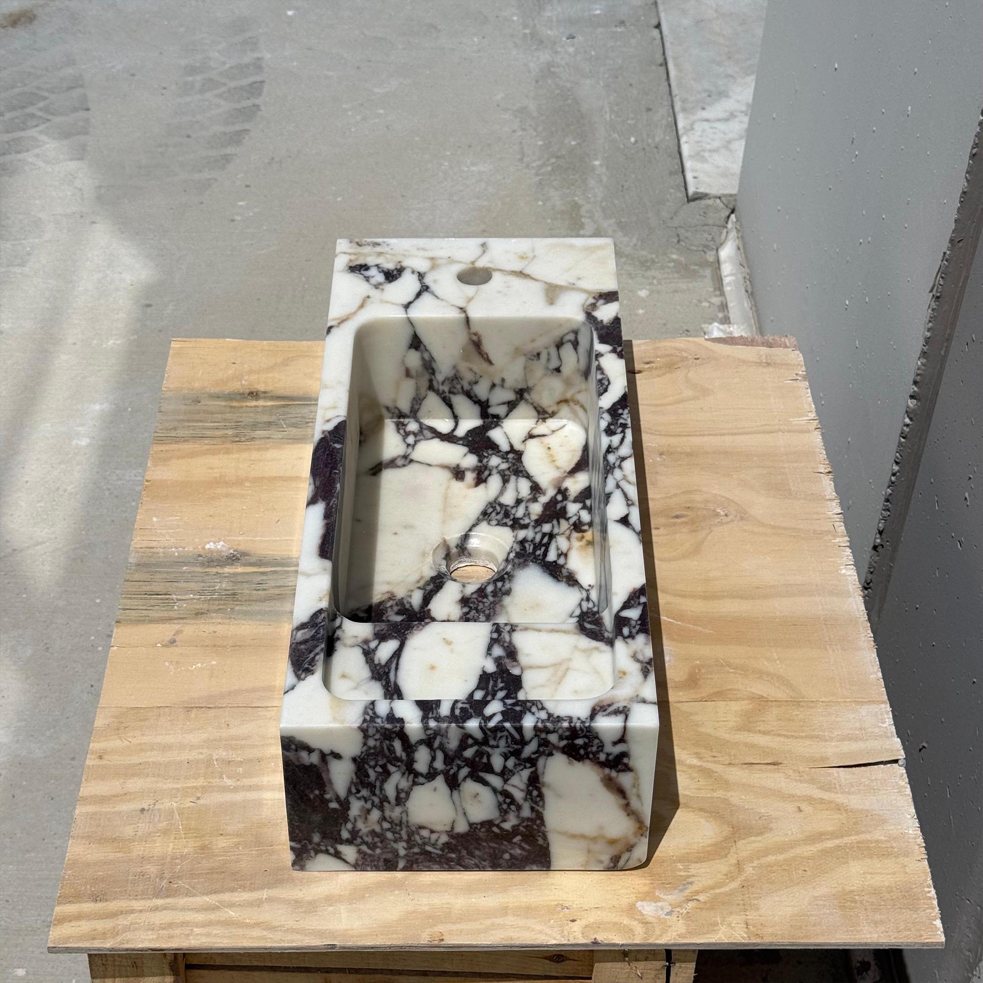 Calacatta Viola stone sink resting on a wooden surface, highlighting its natural beauty and craftsmanship.