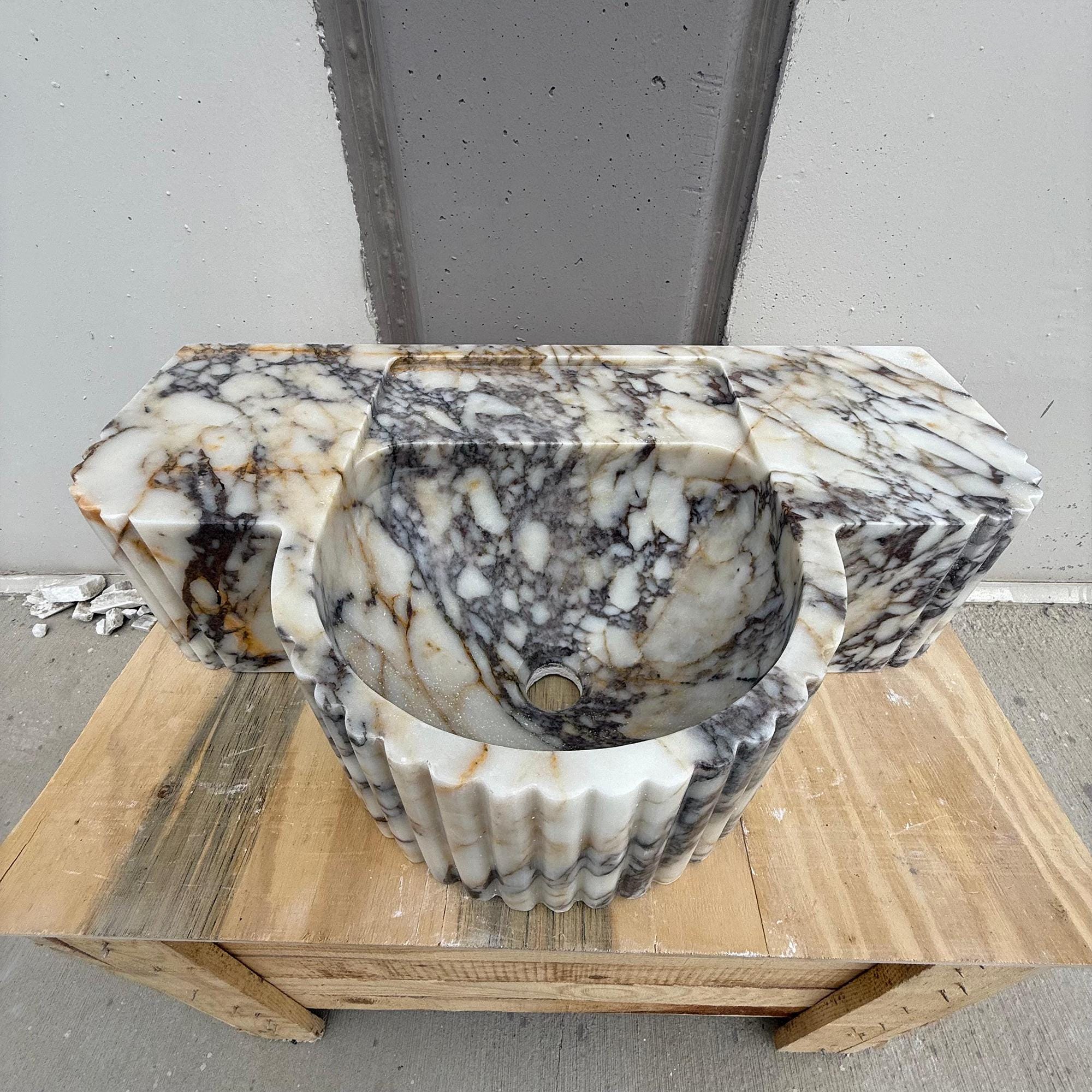 Fluted Calacatta Viola marble sink with sculpted oval basin and bold veining