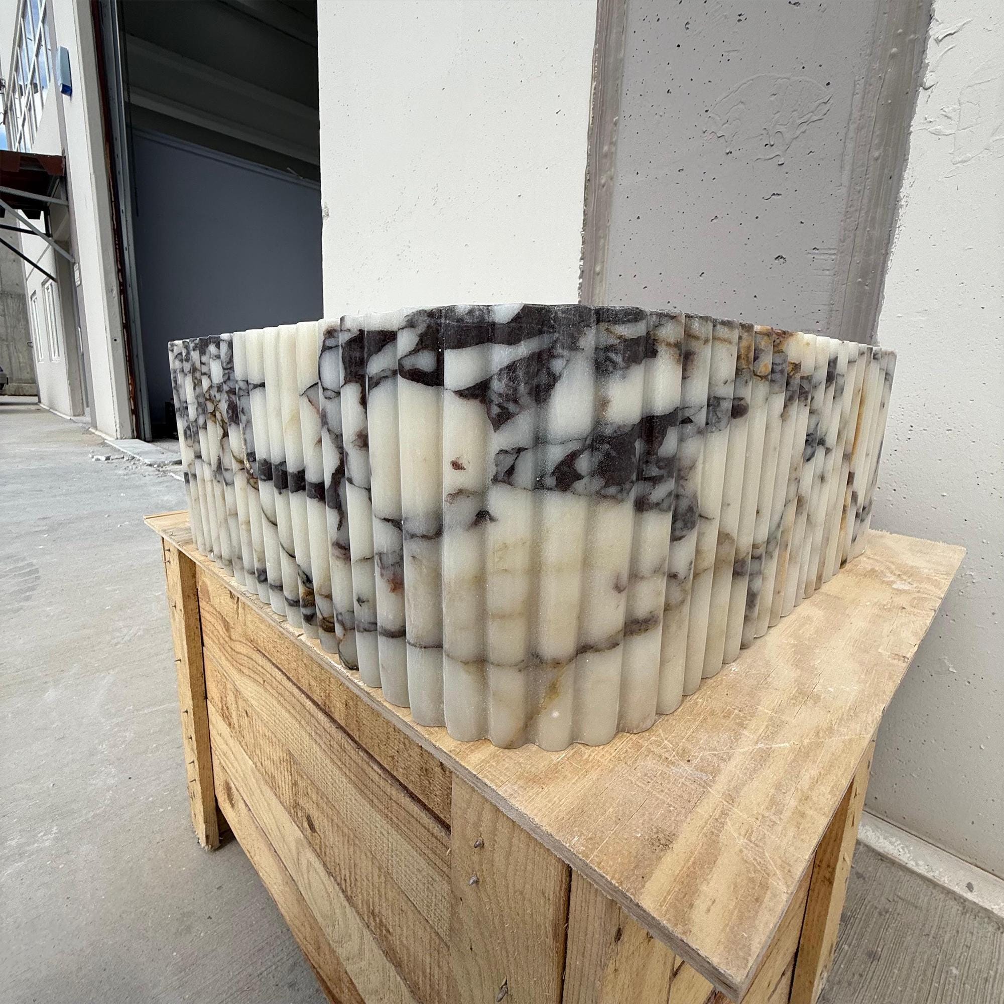 A sculptural square sink carved from Calacatta Viola marble, designed for elegant powder rooms and luxury vanities.