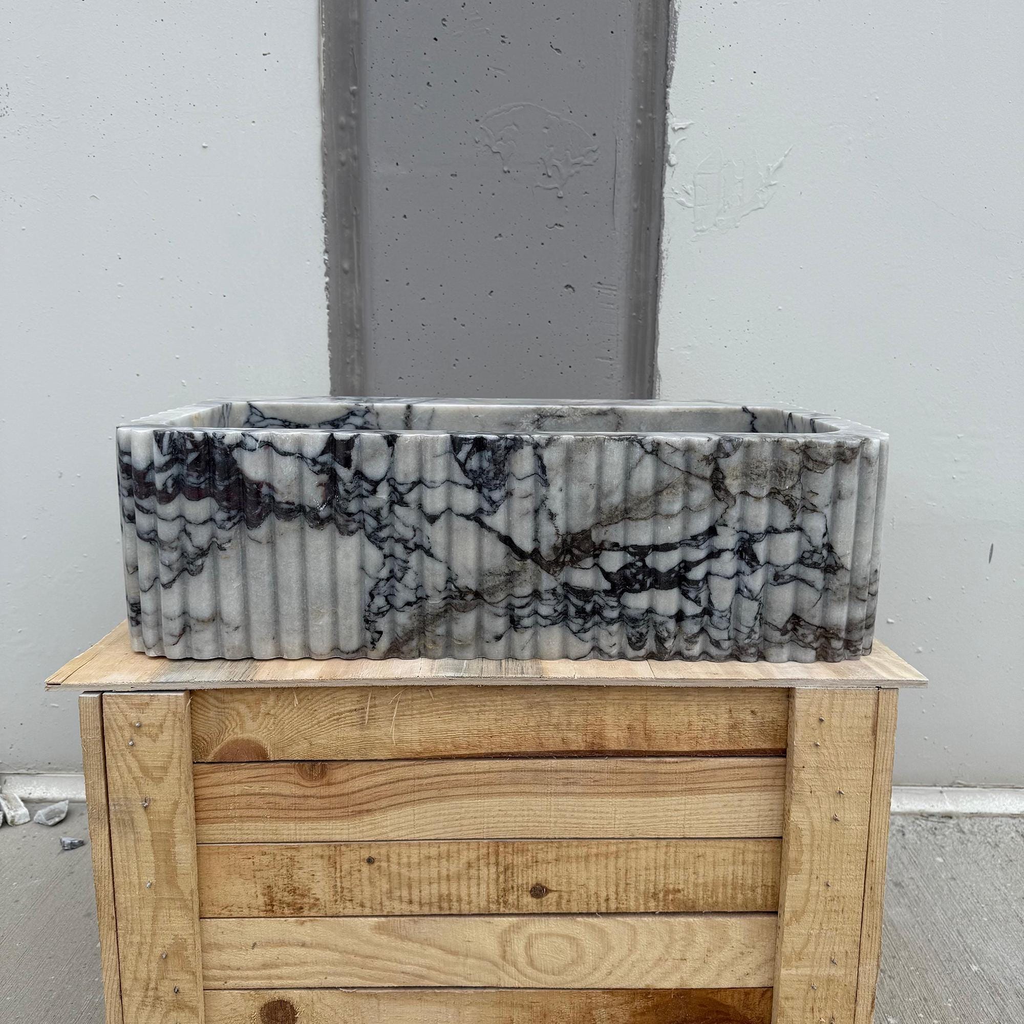 The image showcases the marble’s deep purple veining contrasted with a light gray base.