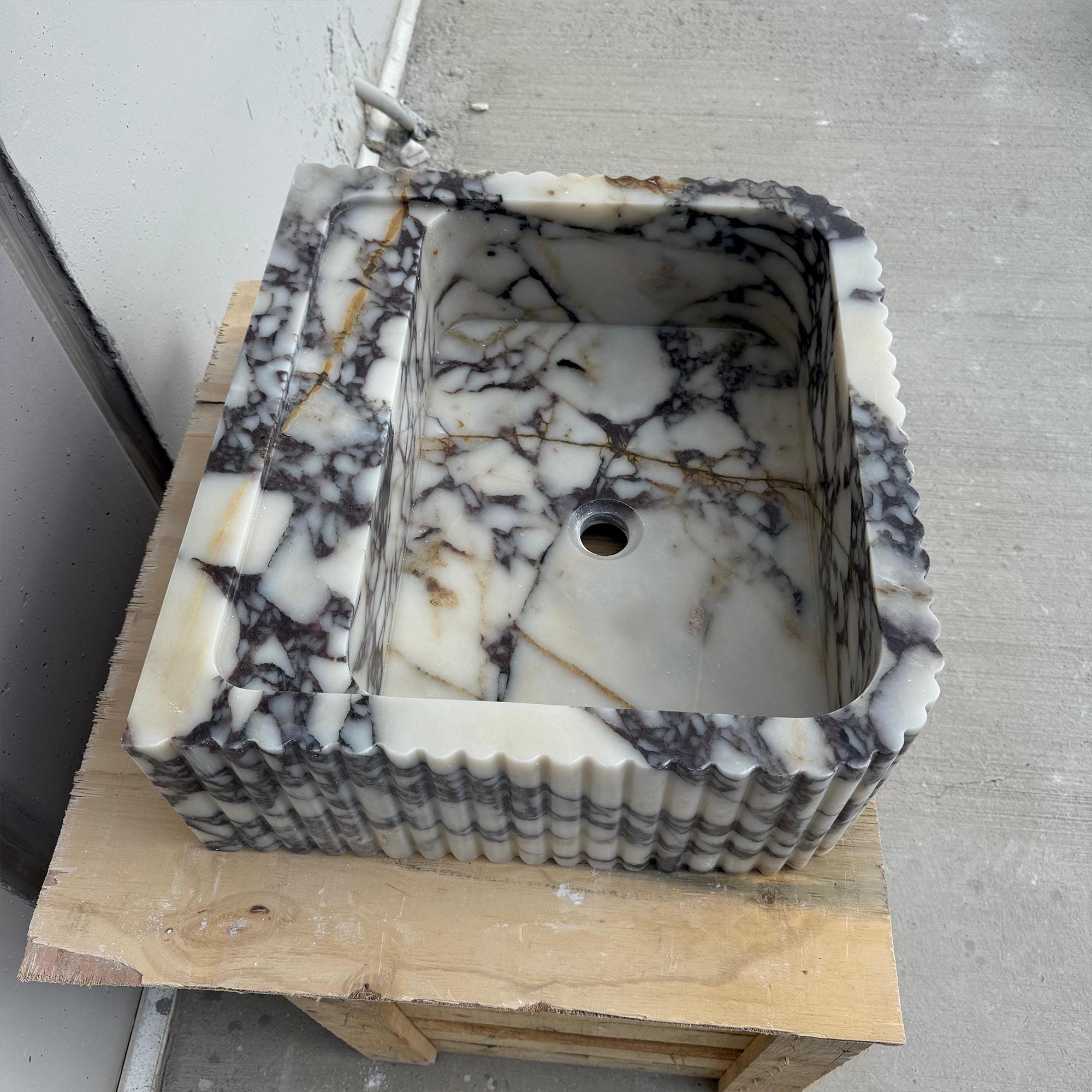 This high-end stone basin features fluted sides, a centered faucet hole, and rich natural veining in Viola marble.