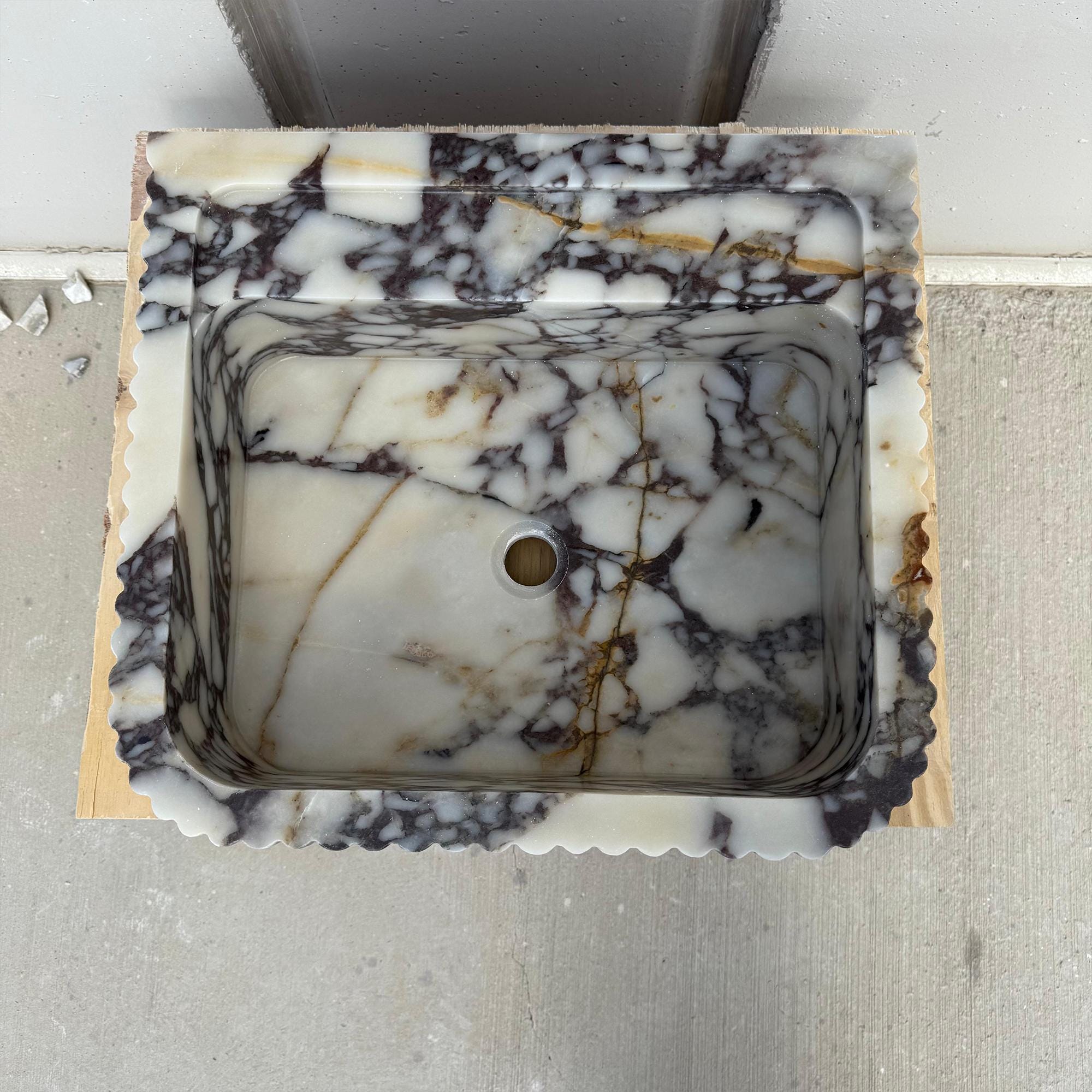 This handcrafted marble sink showcases bold Calacatta Viola veining and a refined square silhouette for upscale interiors.