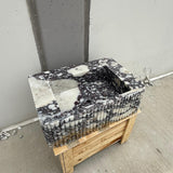 Ribbed Calacatta Viola marble sink with deep purple veining on wood crate