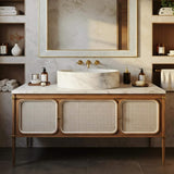 A refined bathroom vanity showcasing a round Carrara marble vessel sink atop a natural wood and rattan cabinet.