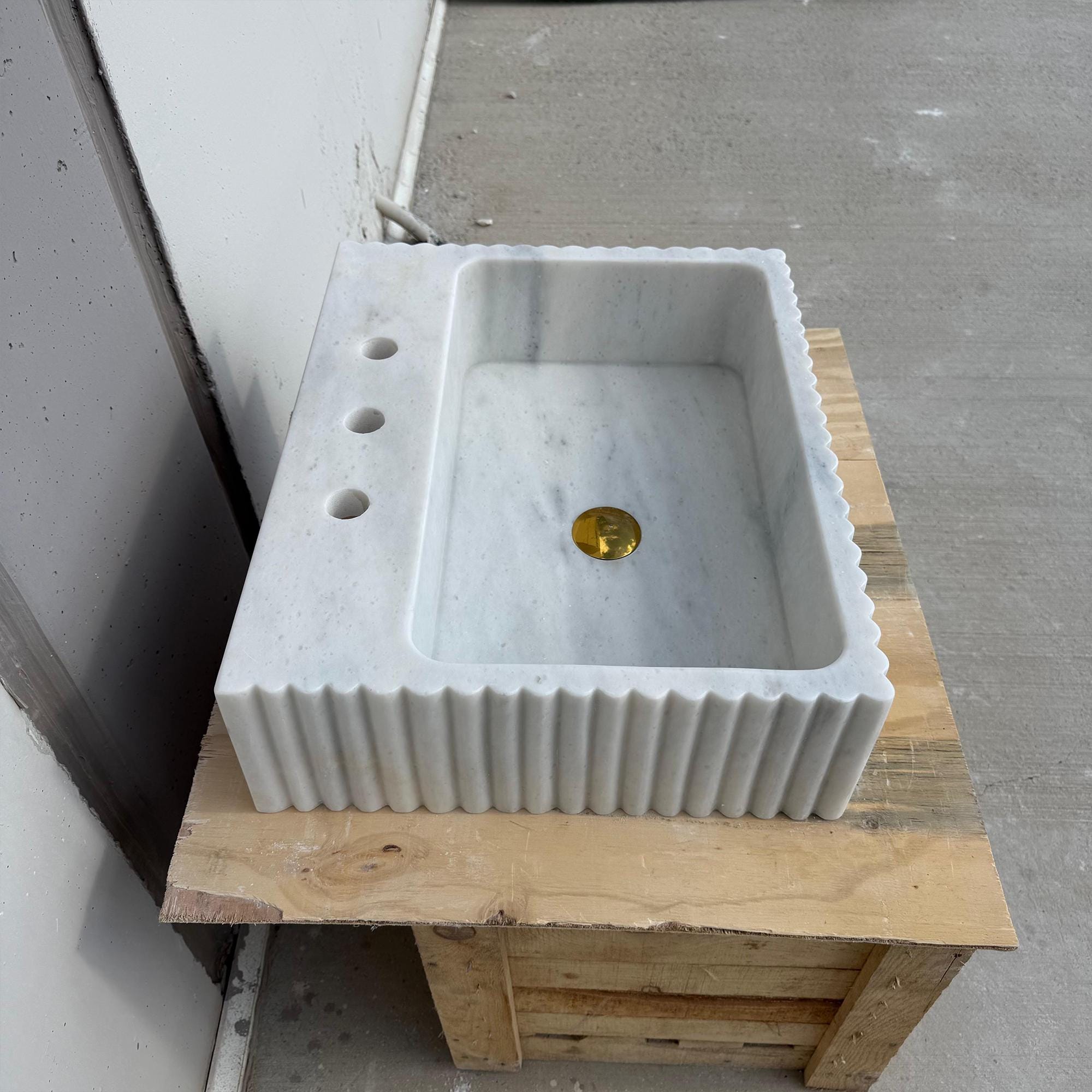 White Carrara bathroom sink on wooden crate, fluted edge design