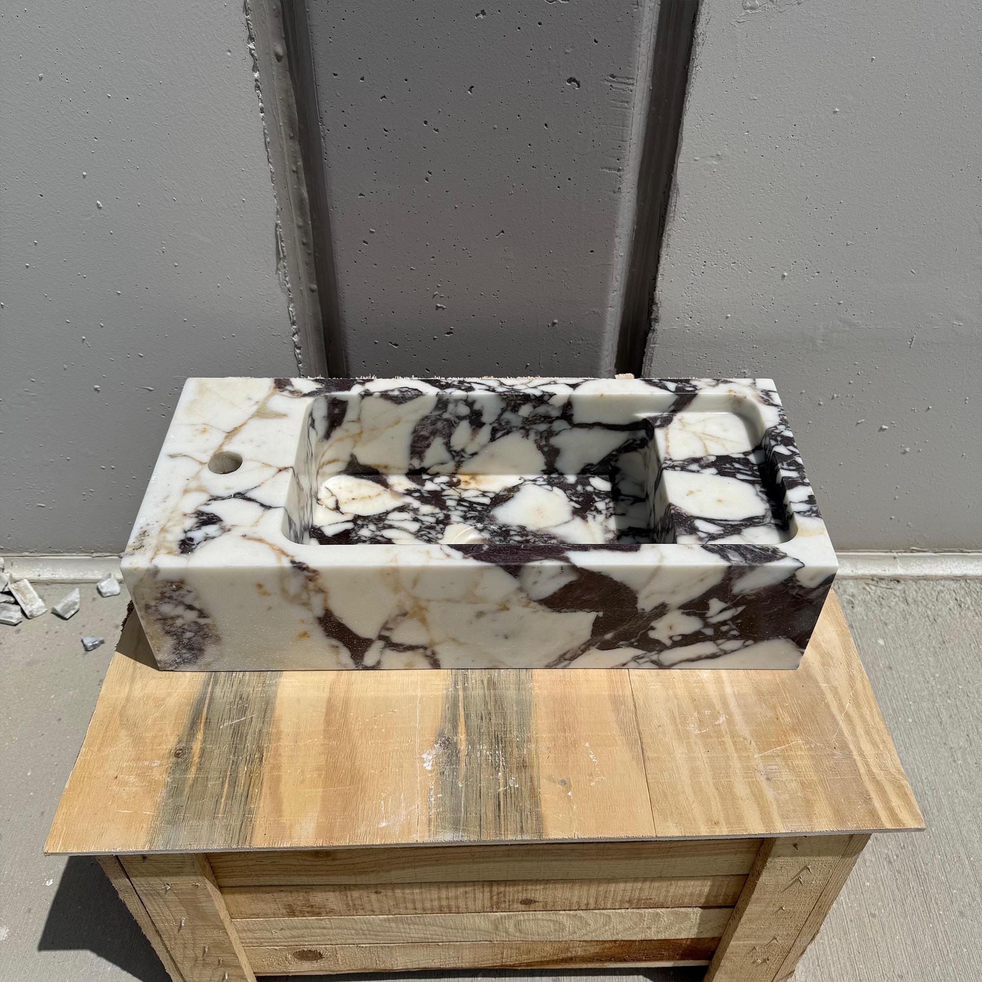 A modern bathroom vanity sink carved from Italian Calacatta Viola marble, ideal for upscale powder rooms.