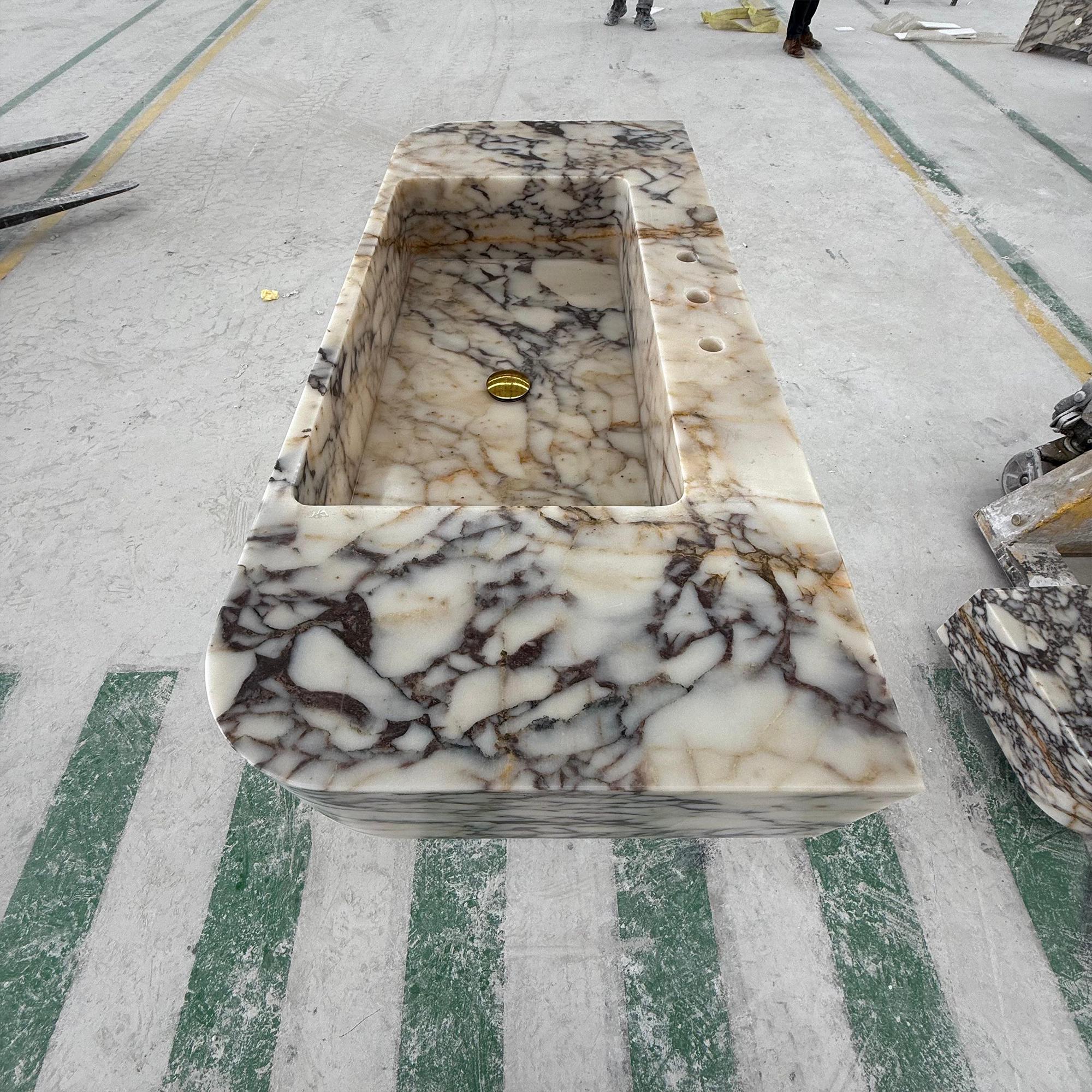 The basin’s sculptural silhouette is enhanced by the rich natural veining of the stone.