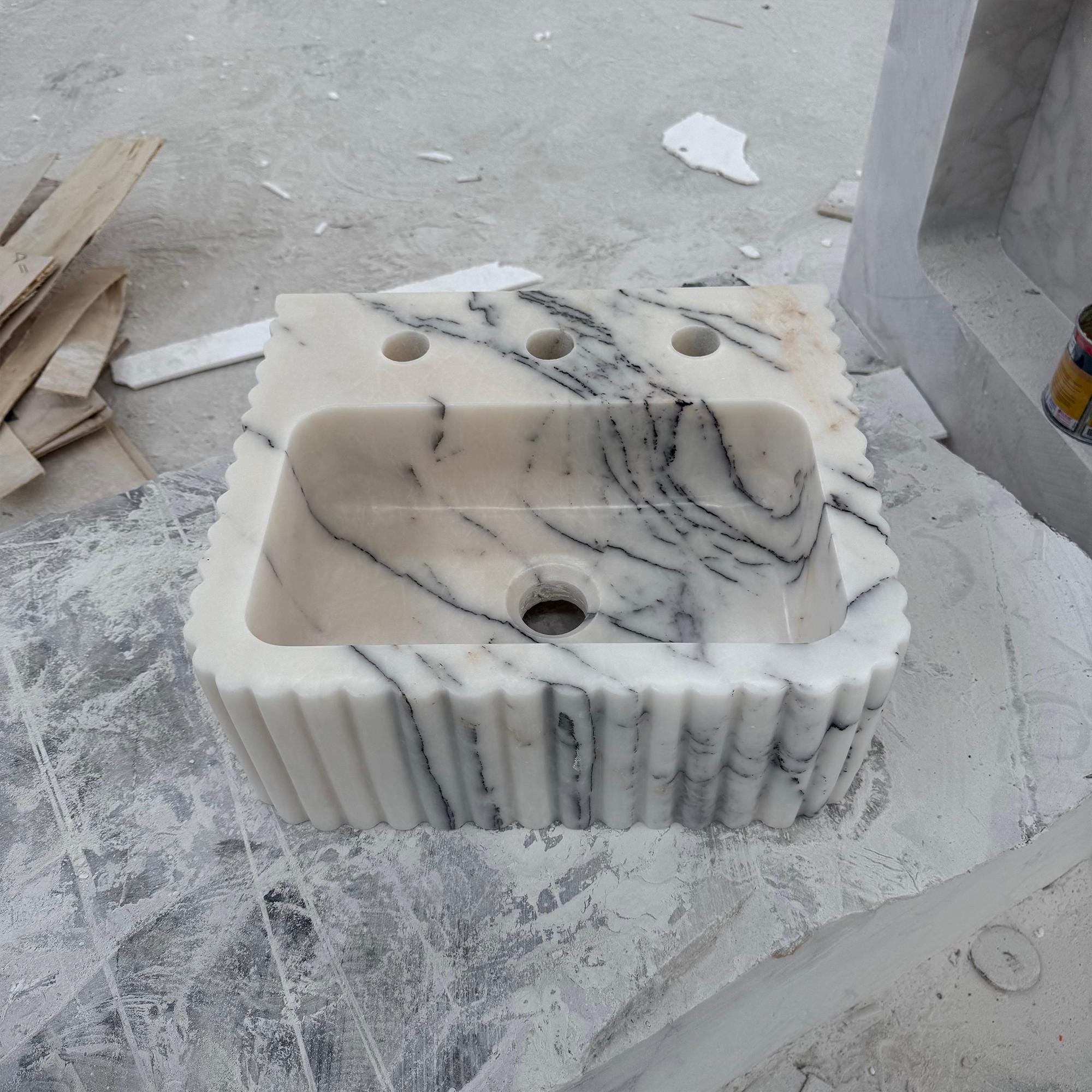 Handcrafted white marble sink with gray veining and fluted edges