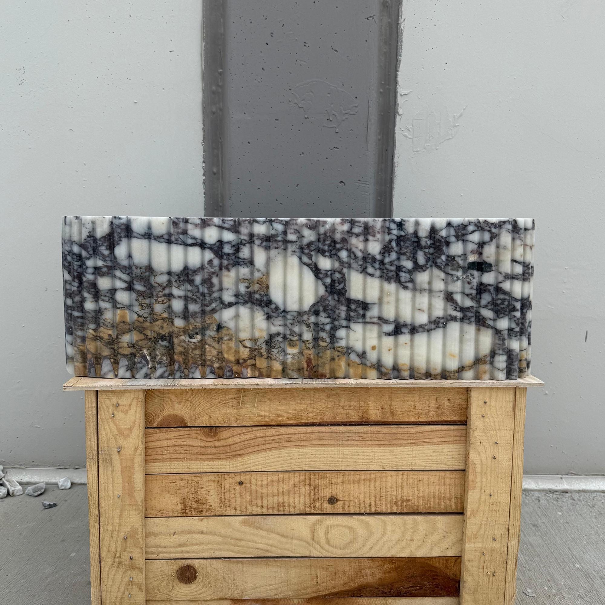 Designer vanity sink in ribbed Calacatta Viola marble with rich veining