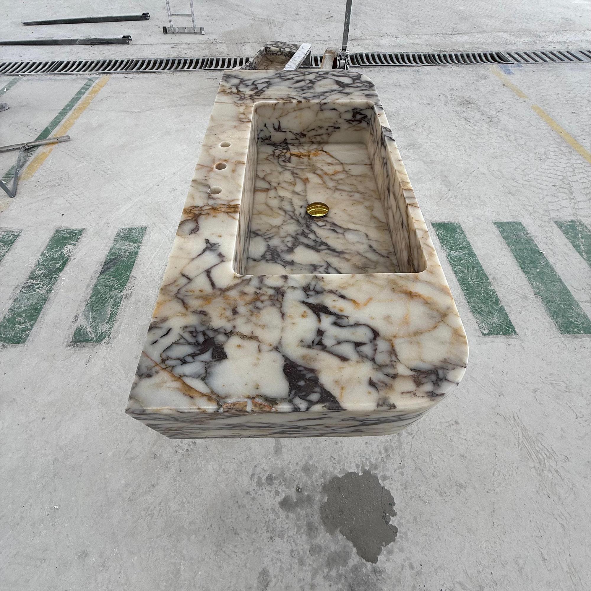 The polished marble surface features deep purple and gold veining throughout the basin.