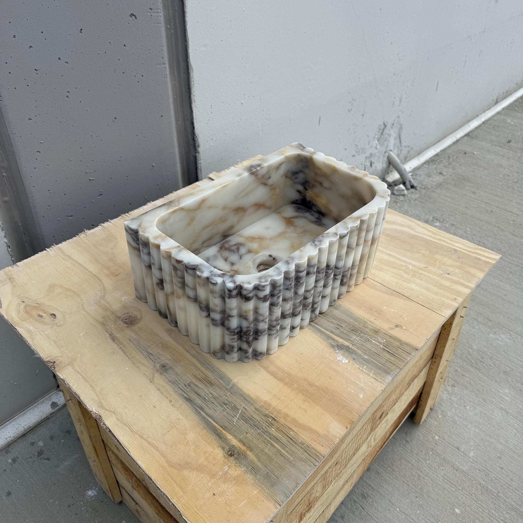 The photo captures a sculpted Carrara marble basin ideal for luxury powder rooms.