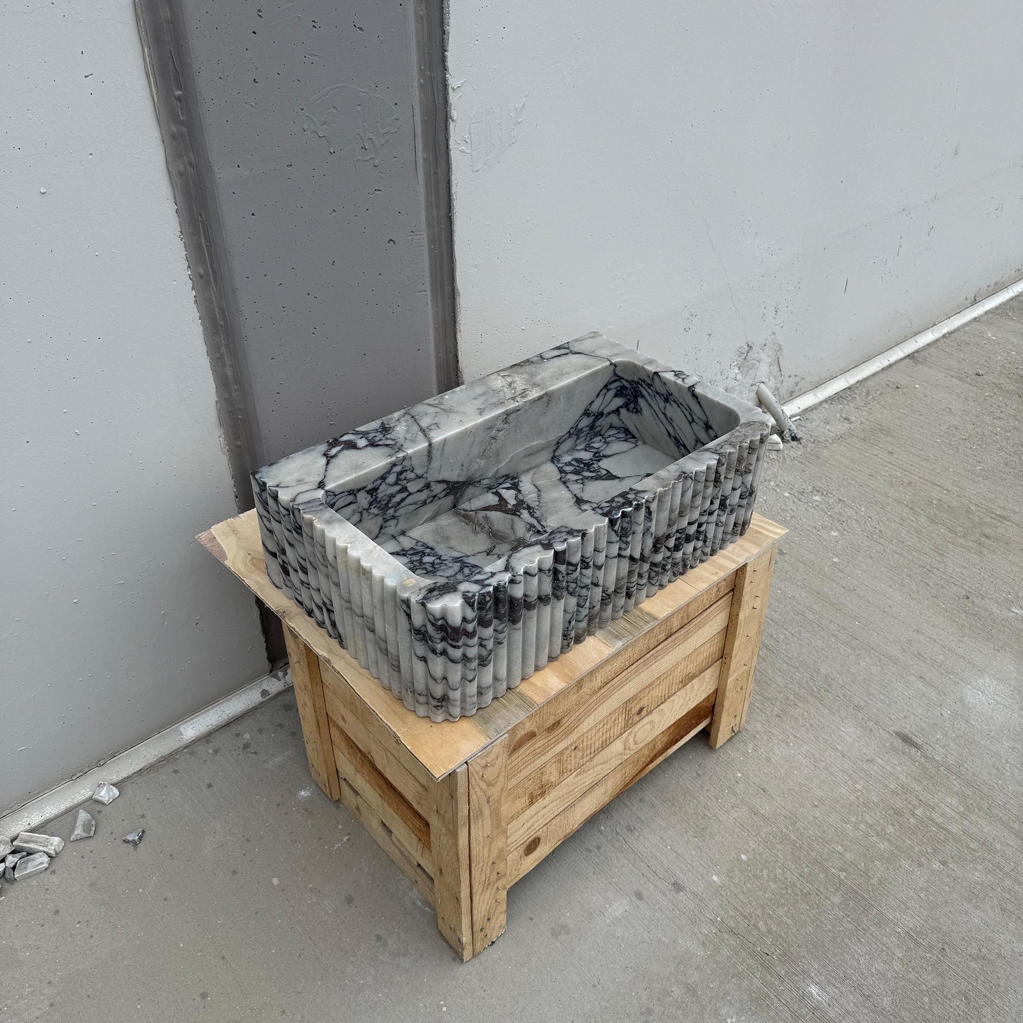 The sink features bold natural patterns with a ribbed texture and polished interior surface.