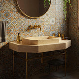 The image shows an octagonal travertine vessel sink set atop a matching stone countertop with brass fixtures.
