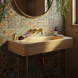 A luxurious travertine wall-mounted sink with golden fixtures in a rustic bathroom setting.